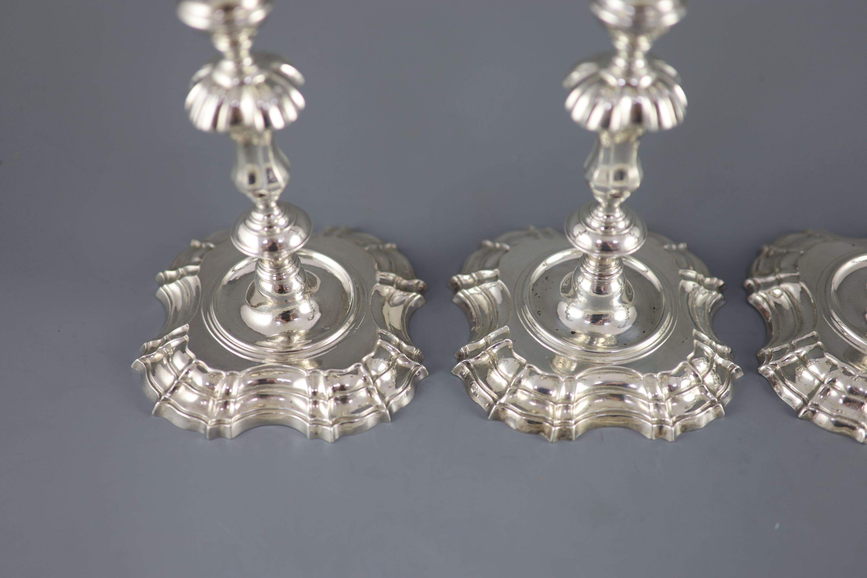 A near set of four George II cast silver candlesticks, by John Cafe